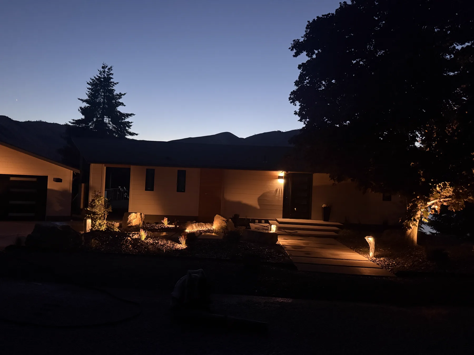 Landscape lighting glowing across a home exterior at night
