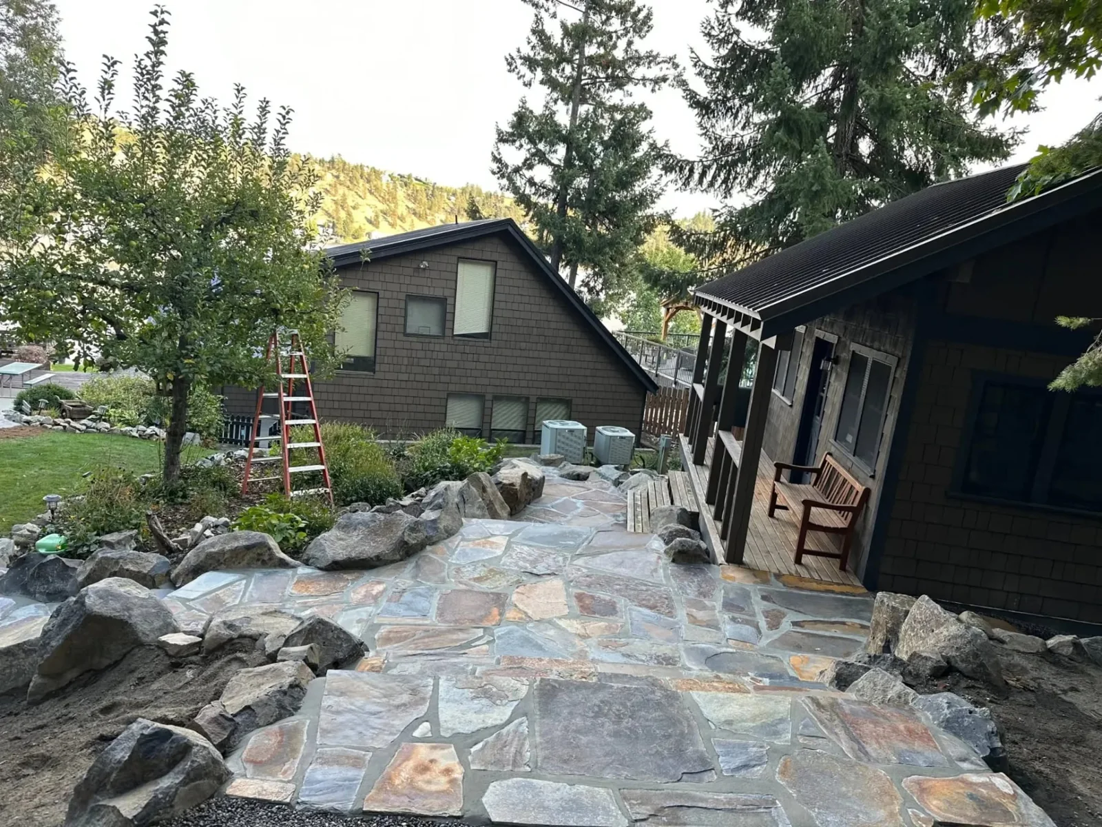 Natural flagstone patio and boulder edging beside a cabin in the trees