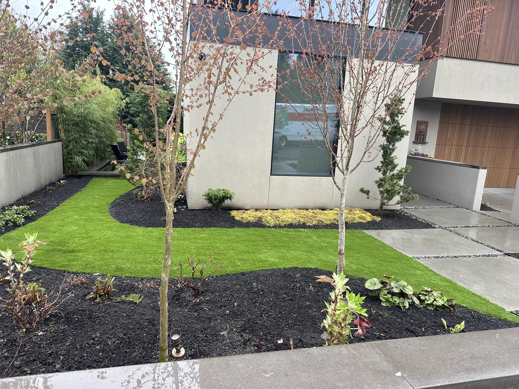 Modern front yard with artificial turf and curved planting beds