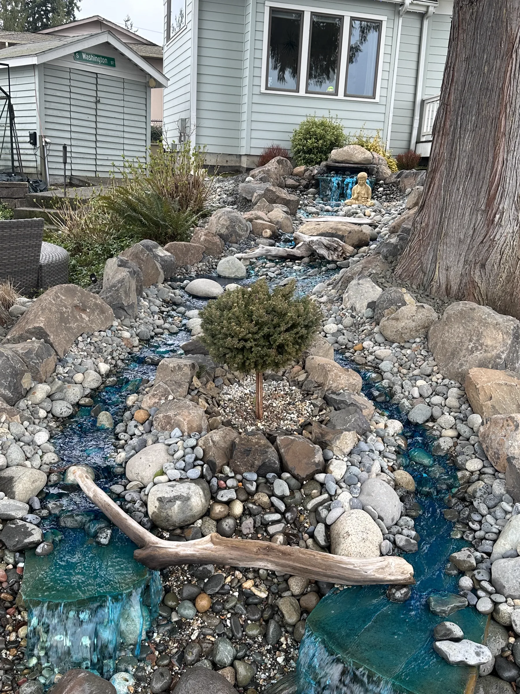 Decorative dry creek bed with river rock and blue glass stone