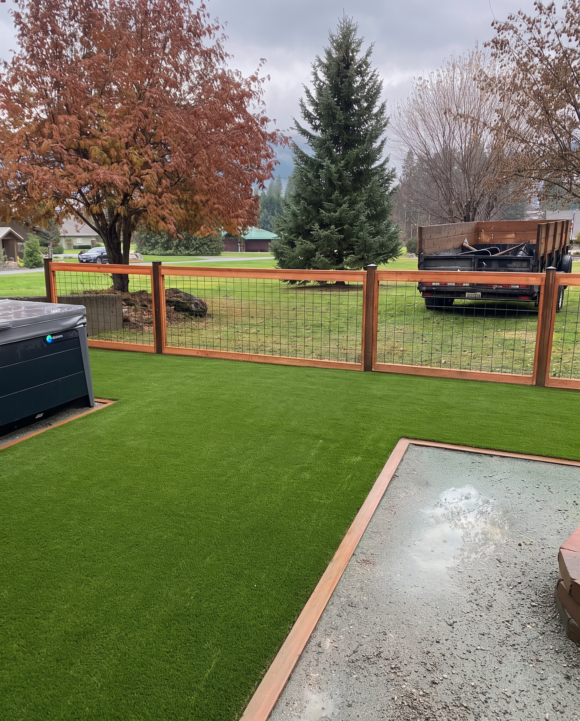 Artificial turf backyard with a hot tub and cedar fence
